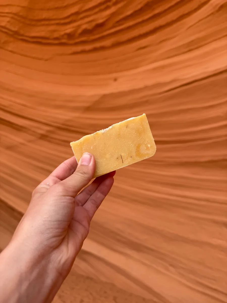Handmade bar soap in warm amber tones against swirling sandstone