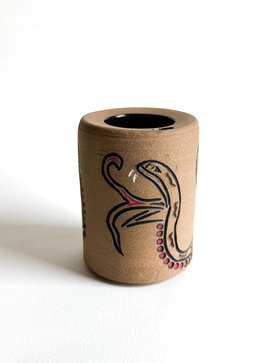 Travel cup with a hand-carved snake design